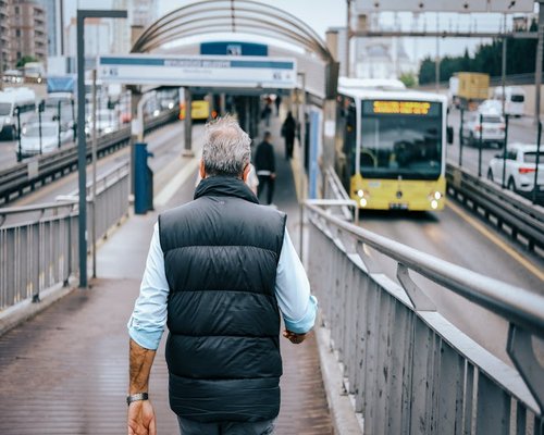 Healthy adult generic citizen walking down an urban green pedestrian pathway next to public transit corridor